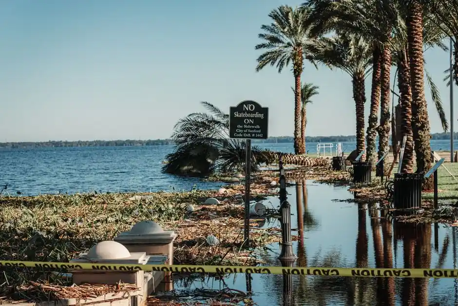 A flooded pathway with caution tape and palm trees by a lake in Sanford, Florida.